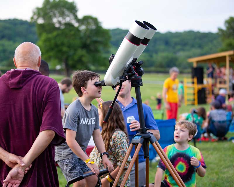 Little boy looking into a telescope.