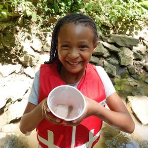 Girl holding tadpole in the creek