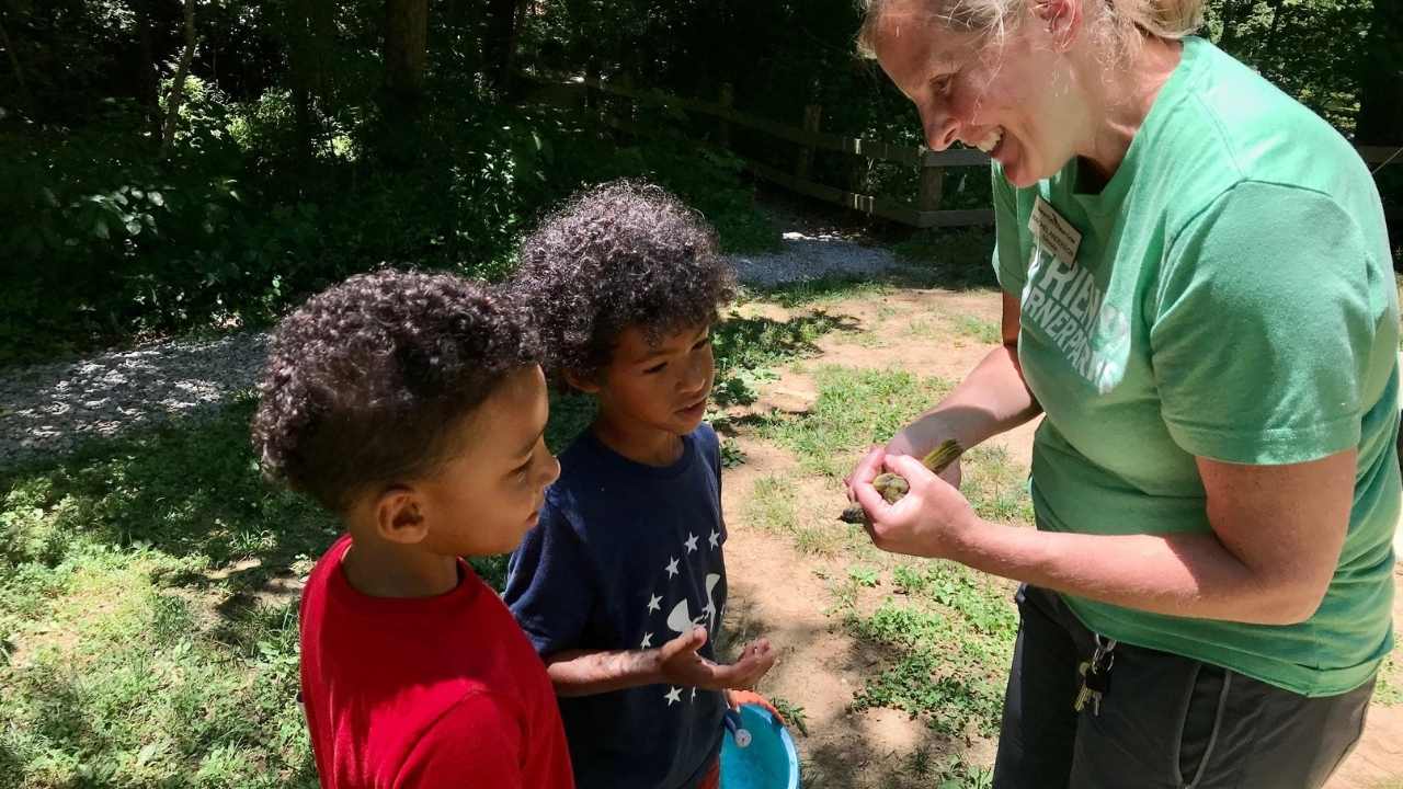 Naturalist showing two children a bird.