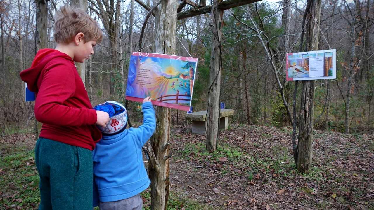 Two children reading a StoryWalk book along the trail.