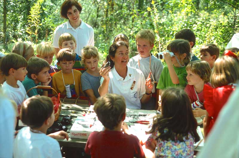 Woman holding a bird while teaching a class of children in the 1970s