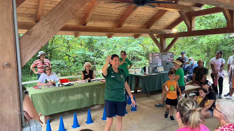 Woman speaking to group of people under picnic shelter